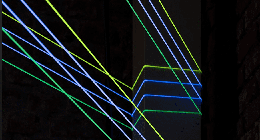 Raggi laser verde neon e blu creano un motivo geometrico dinamico, perfetto per una comunicazione creativa o eventi ed esperienze uniche.